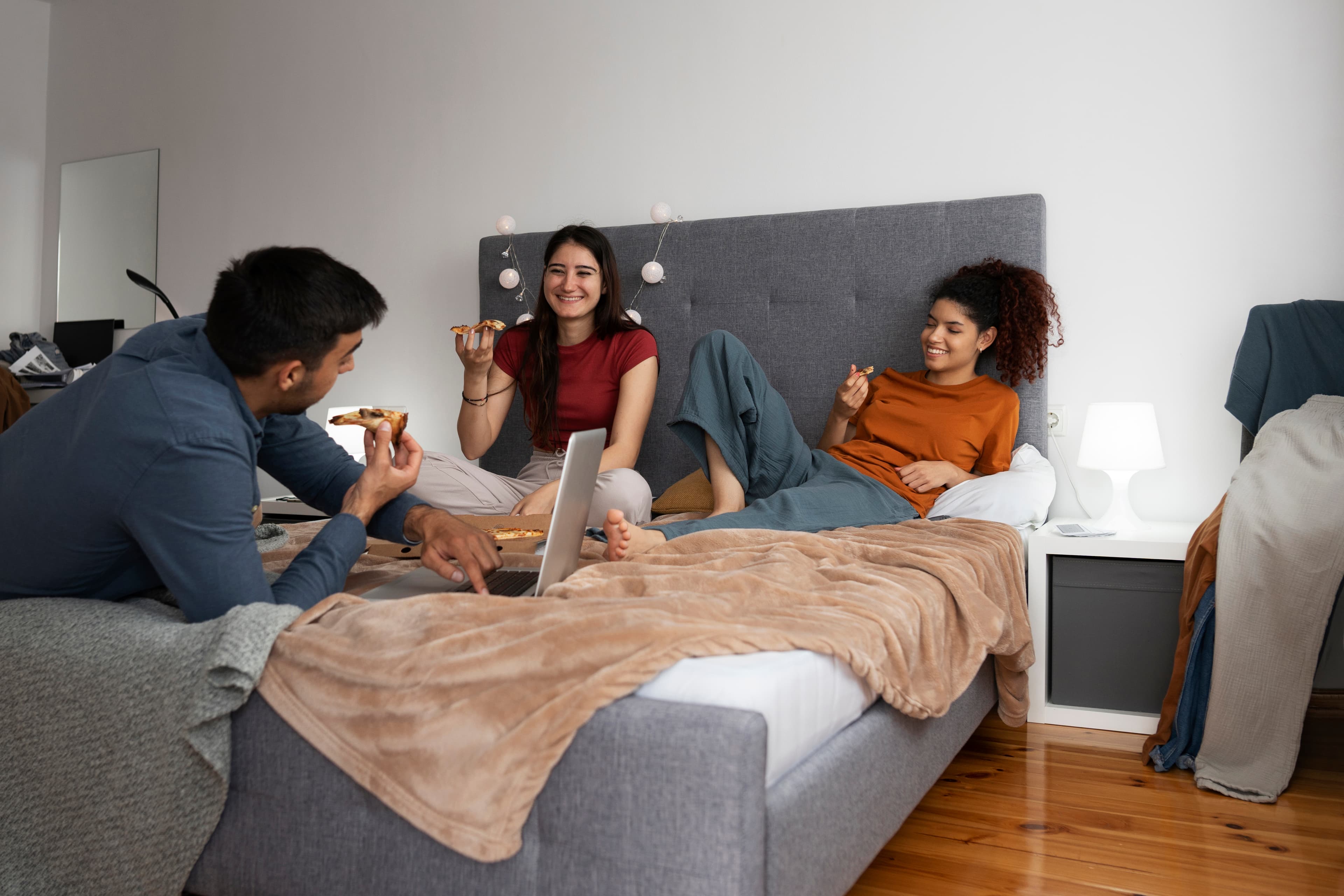 Three flatmates relaxing and chatting in a bedroom