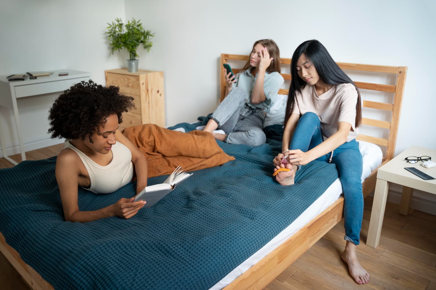 Three flatmates spending time together in a bedroom